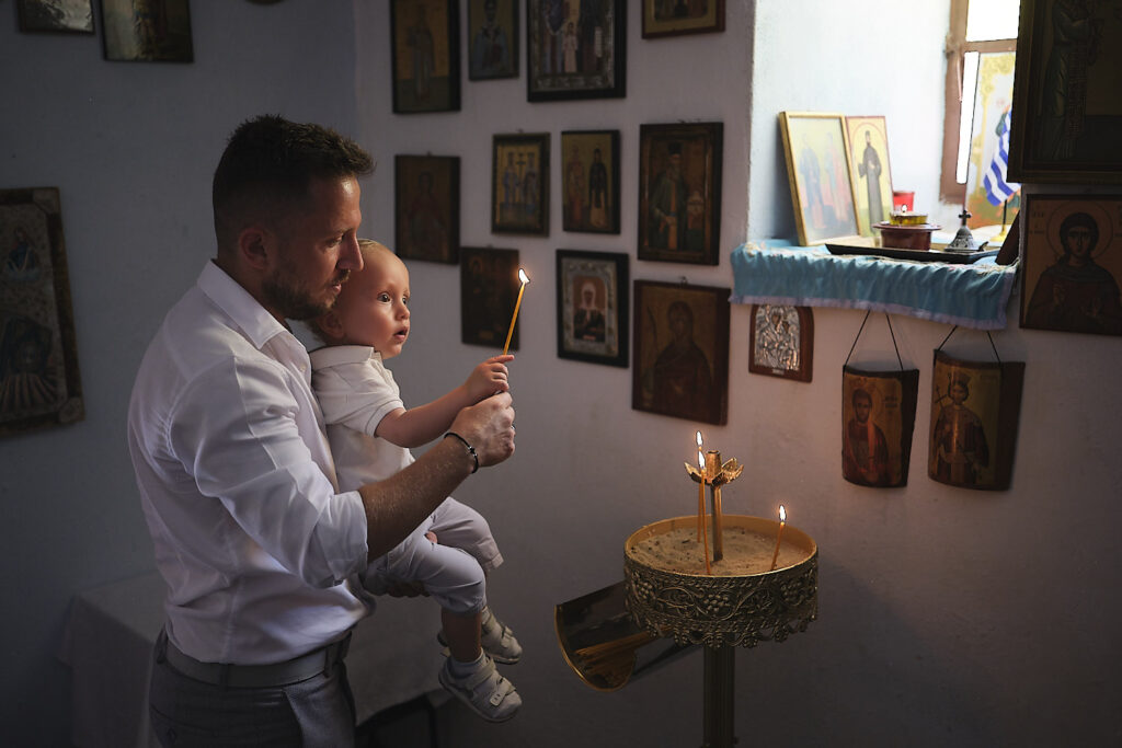 ανάβουν ένα κεράκι ο μπαμπας με το μωρό πτιν απο την βάπτιση